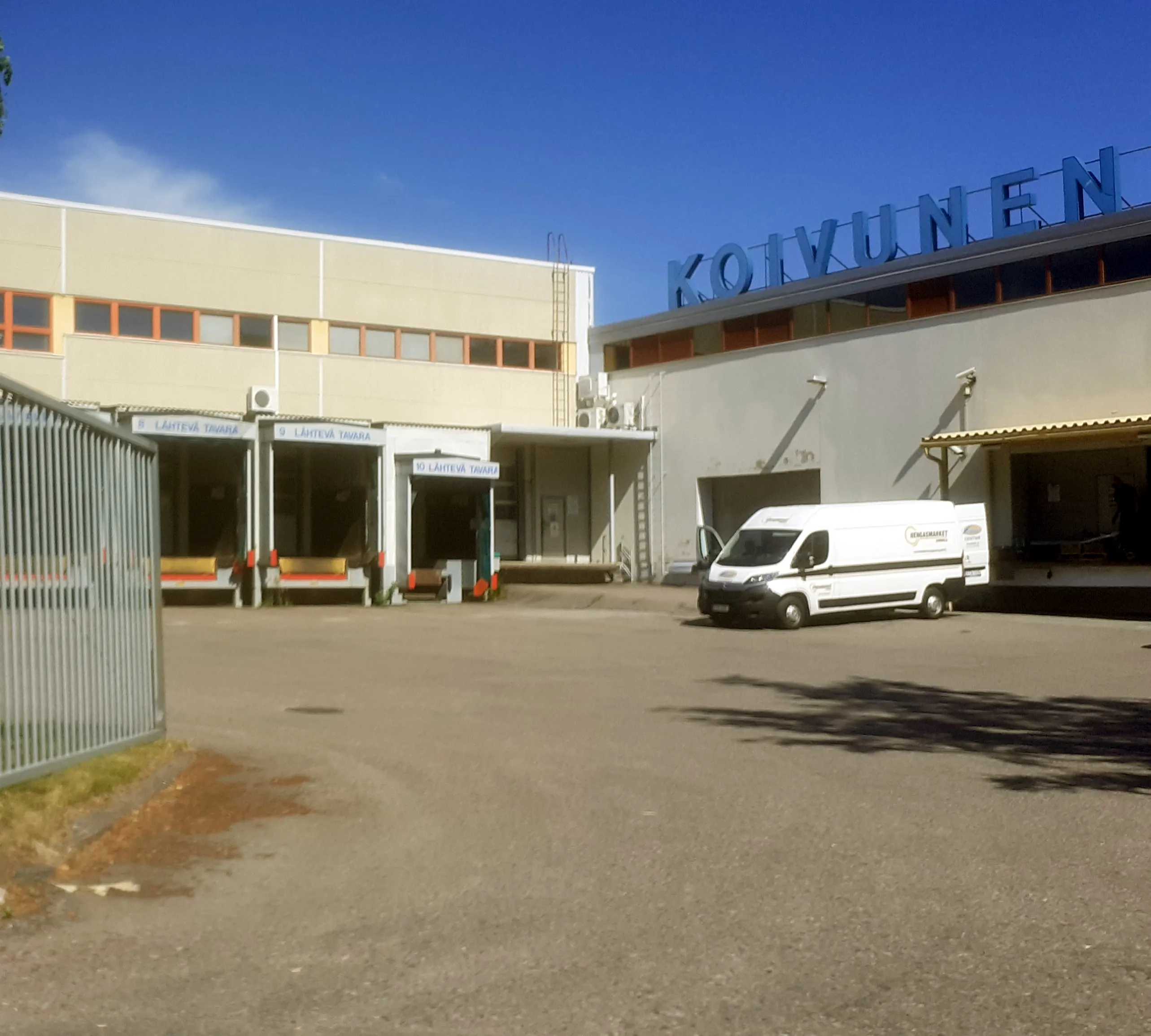Fenced distribution-yard entrance with loading docks behind